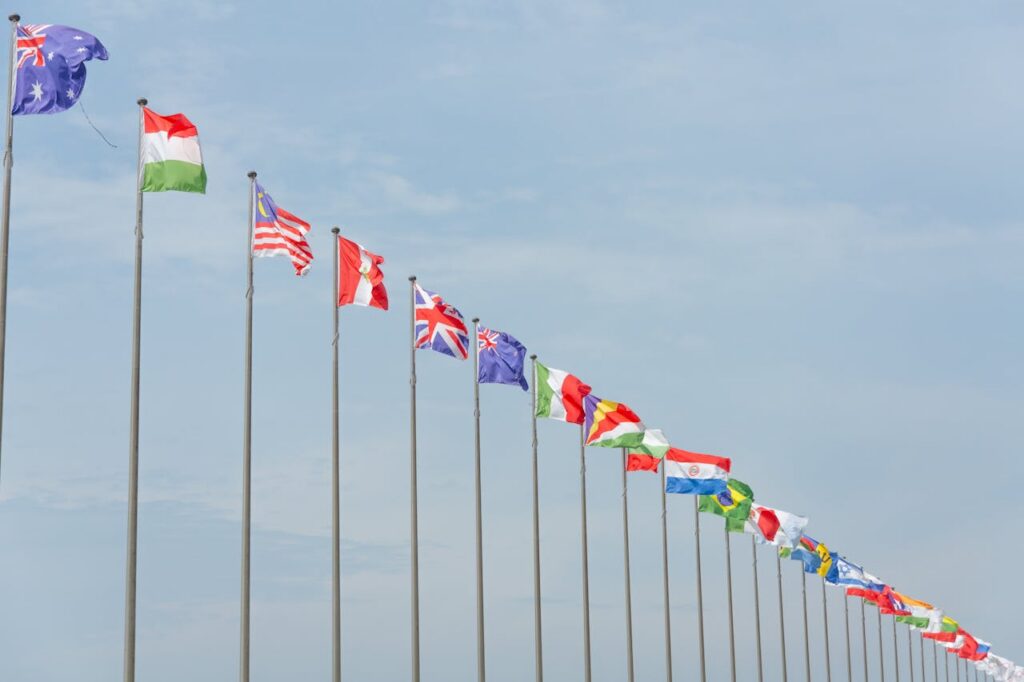 A series of international flags flying in a line against a clear blue sky